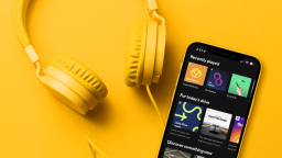 phone with spotify premium app open next to yellow headphones